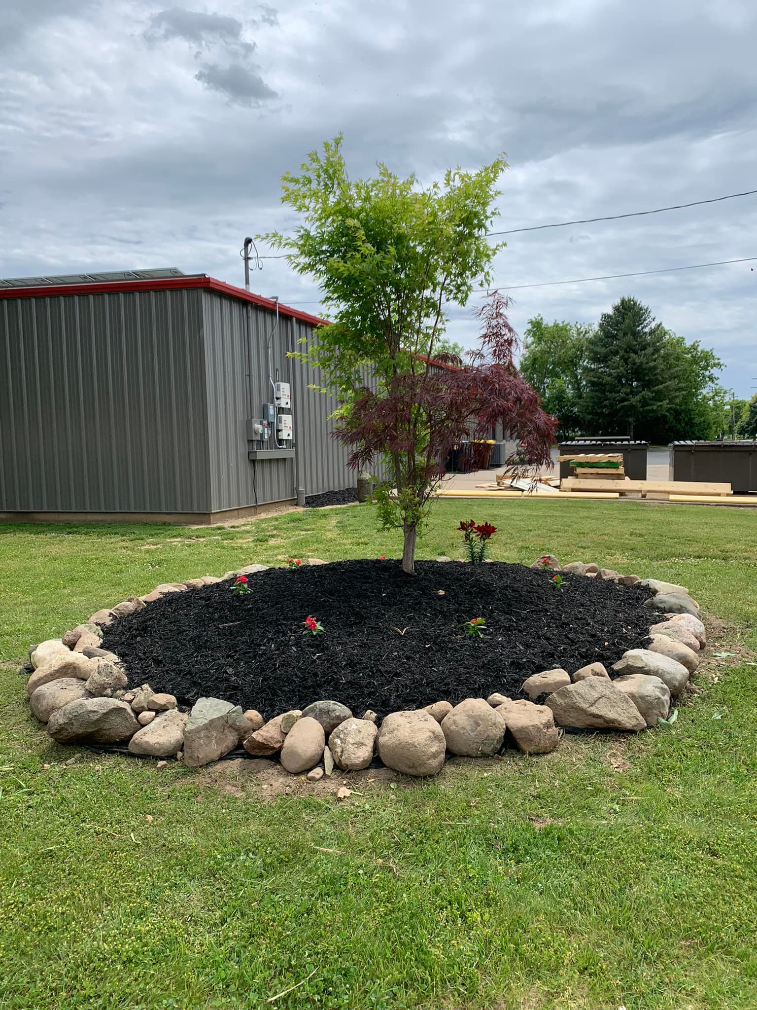Beautifully landscaped garden bed accented with natural stone edging, seamlessly blending lush greenery and tasteful hardscape elements.